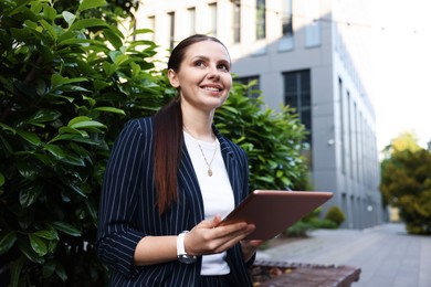 Photo of Successful businesswoman with tablet near office building