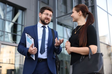Photo of Happy coworkers discussing something near office building