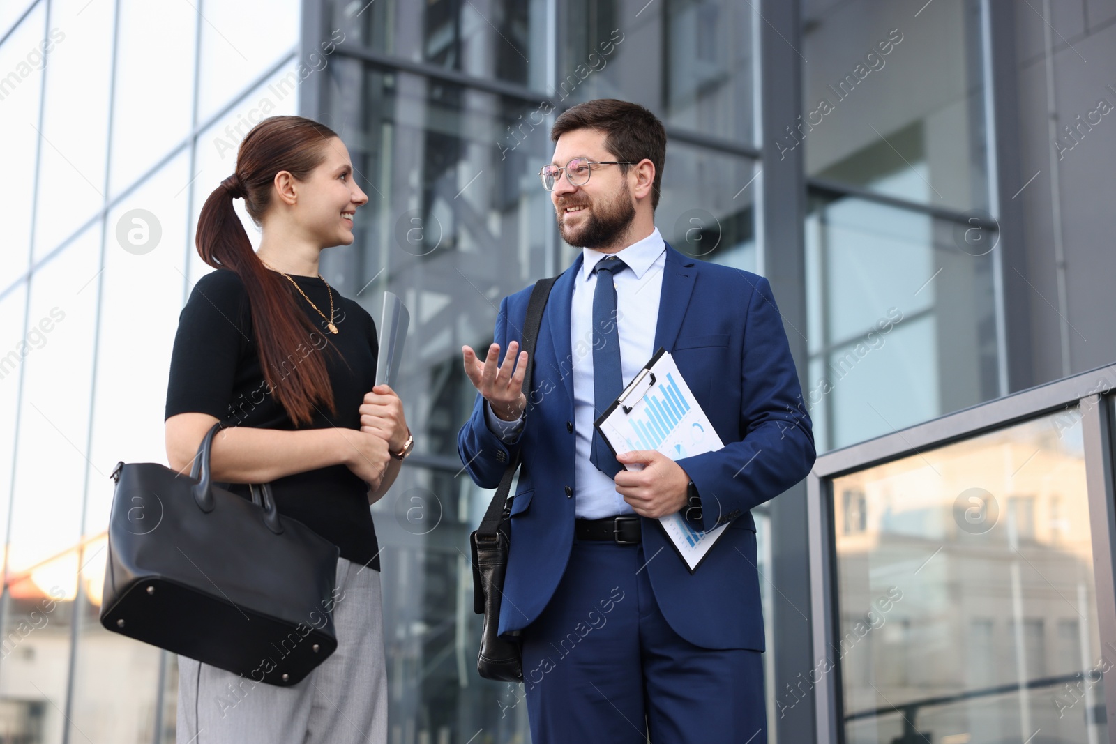 Happy coworkers discussing something near office building Photo of Happy coworkers discussing something near office building