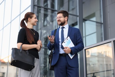 Photo of Happy coworkers discussing something near office building