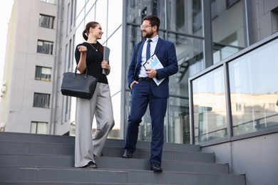 Photo of Happy coworkers discussing something near office building