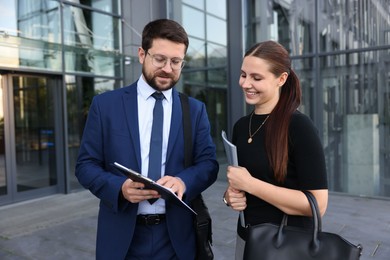 Photo of Happy coworkers discussing something near office building