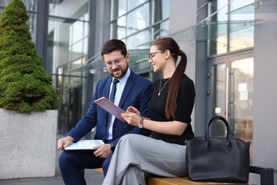 Photo of Happy coworkers with tablet discussing something near office building