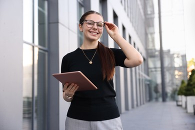 Photo of Successful businesswoman with tablet near office building