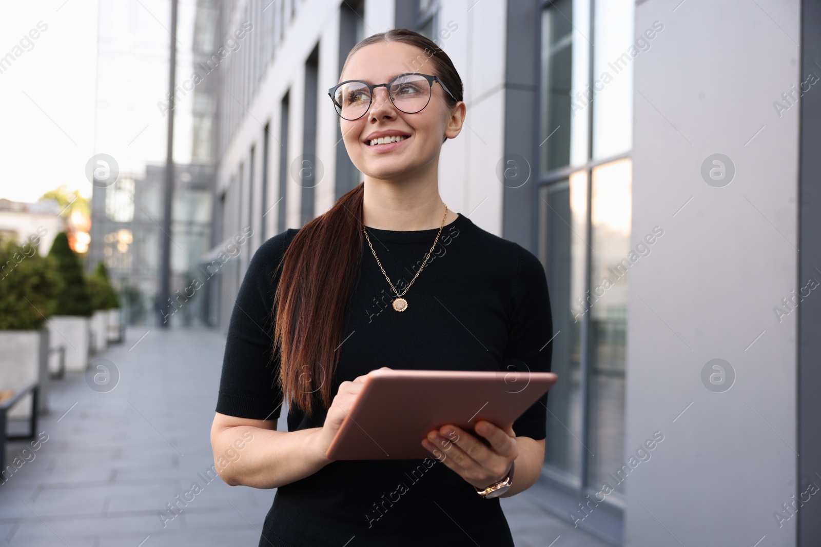 Photo of Successful businesswoman with tablet near office building