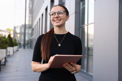 Photo of Successful businesswoman with tablet near office building