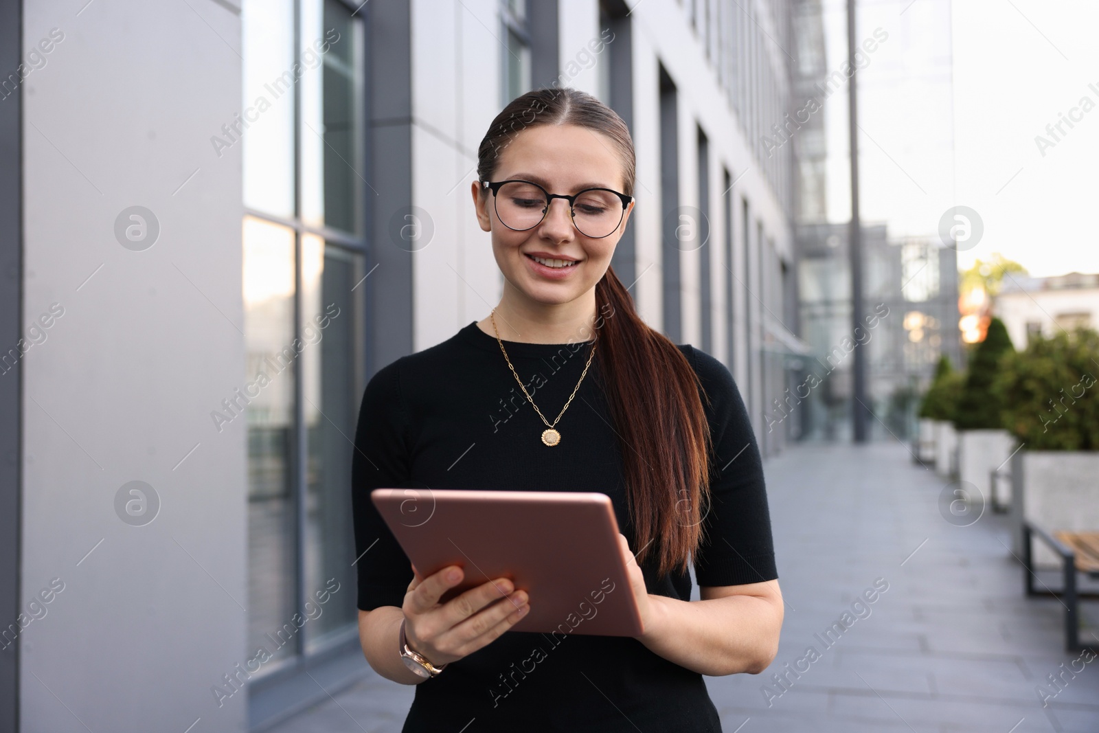 Photo of Successful businesswoman with tablet near office building