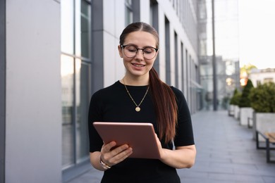 Photo of Successful businesswoman with tablet near office building