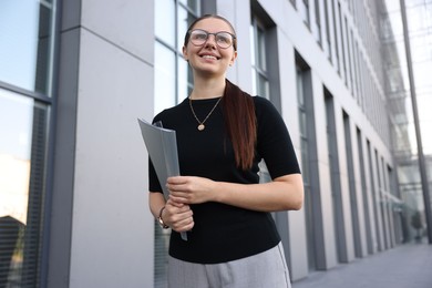 Photo of Successful businesswoman with folder near office building