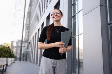 Photo of Successful businesswoman with folder near office building