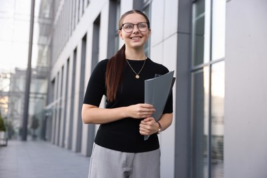 Photo of Successful businesswoman with folder near office building