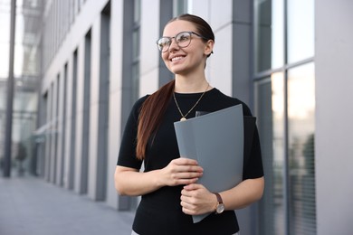 Photo of Successful businesswoman with folder near office building