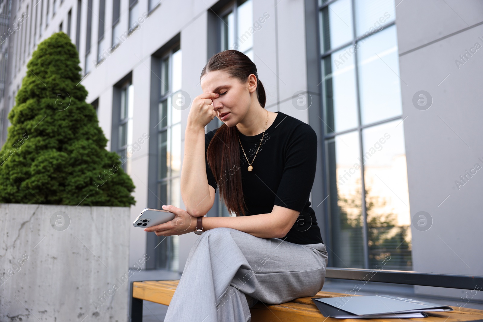 Photo of Tired businesswoman on bench outside office building
