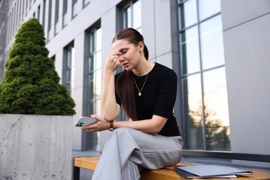 Photo of Tired businesswoman on bench outside office building