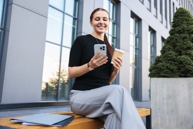 Photo of Successful businesswoman with coffee and smartphone near office building