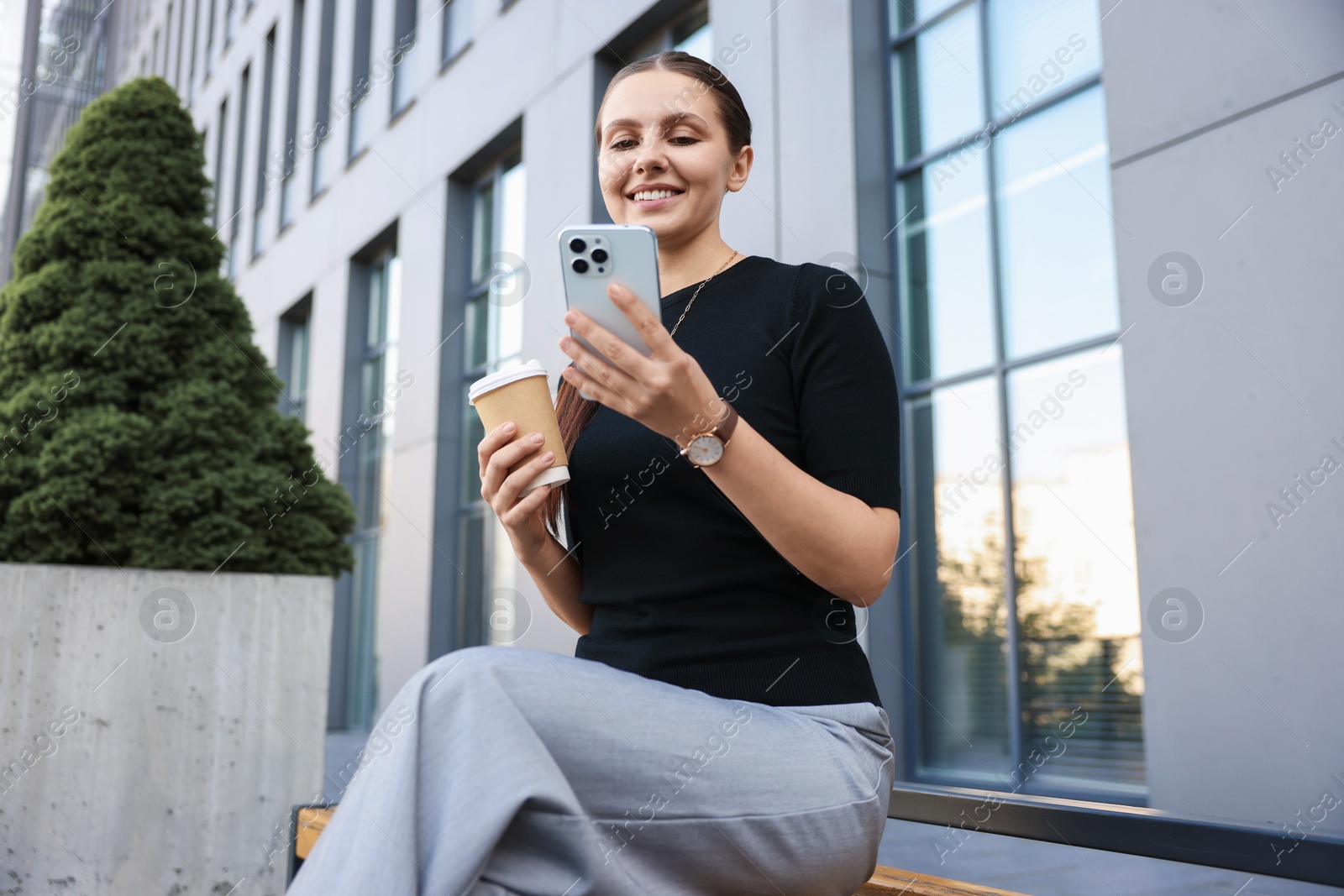Photo of Successful businesswoman with coffee and smartphone near office building