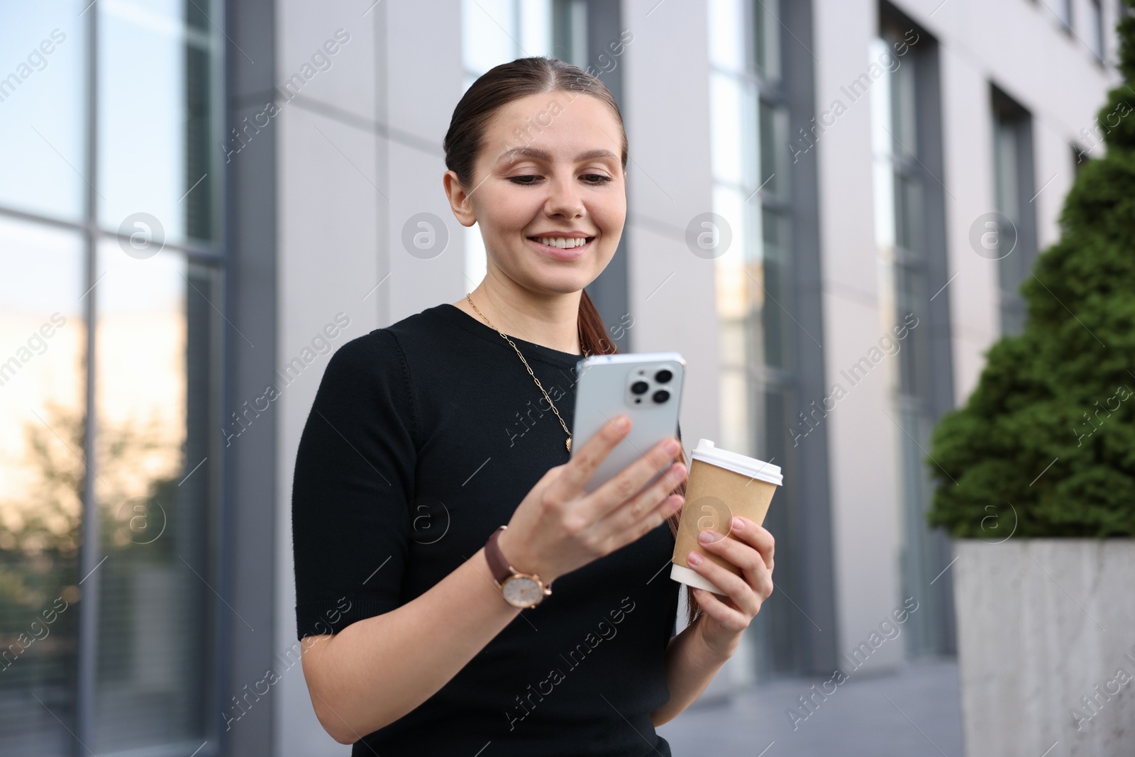 Photo of Successful businesswoman with coffee and smartphone near office building