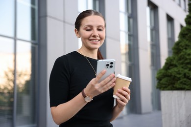 Photo of Successful businesswoman with coffee and smartphone near office building
