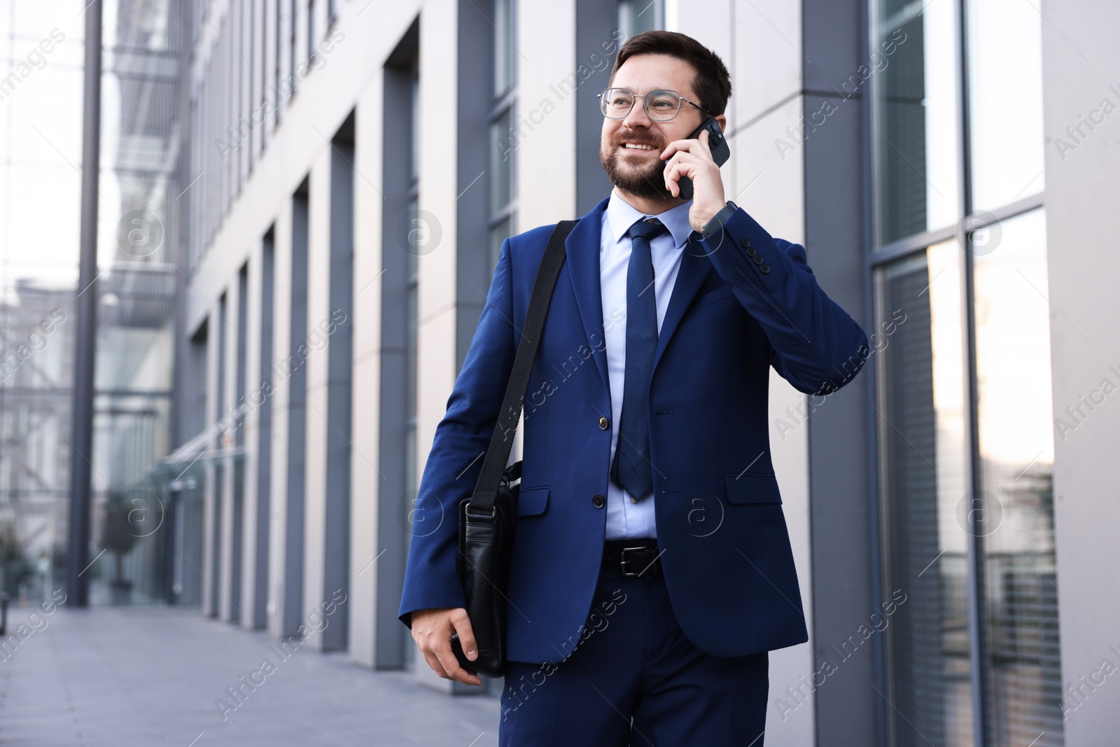 Successful businessman talking on phone near office building. Space for text Photo of Successful businessman talking on phone near office building. Space for text