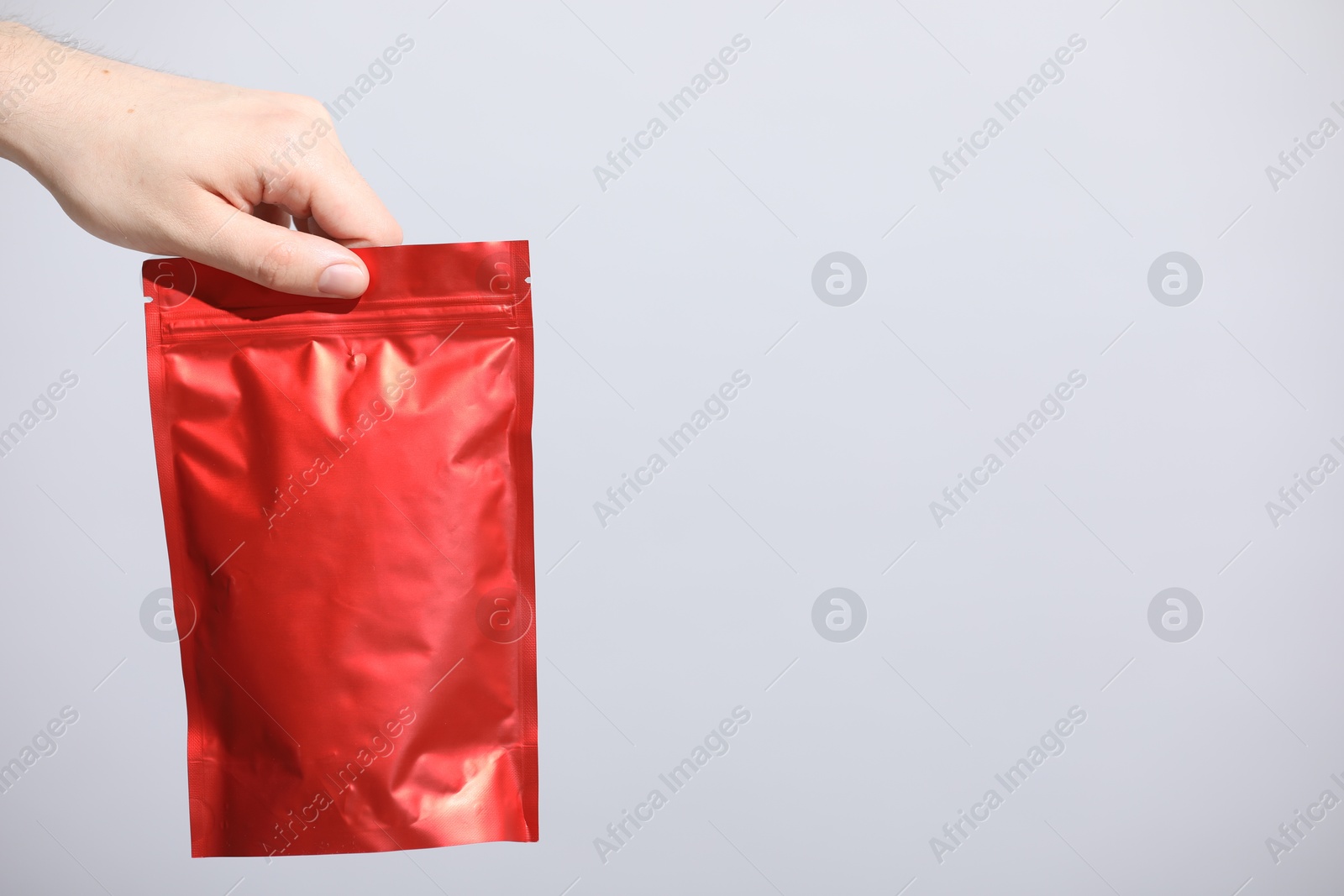 Woman holding blank zipper stand-up pouch on light grey background, closeup. Space for text Photo of Woman holding blank zipper stand-up pouch on light grey background, closeup. Space for text