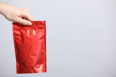 Photo of Woman holding blank zipper stand-up pouch on light grey background, closeup. Space for text