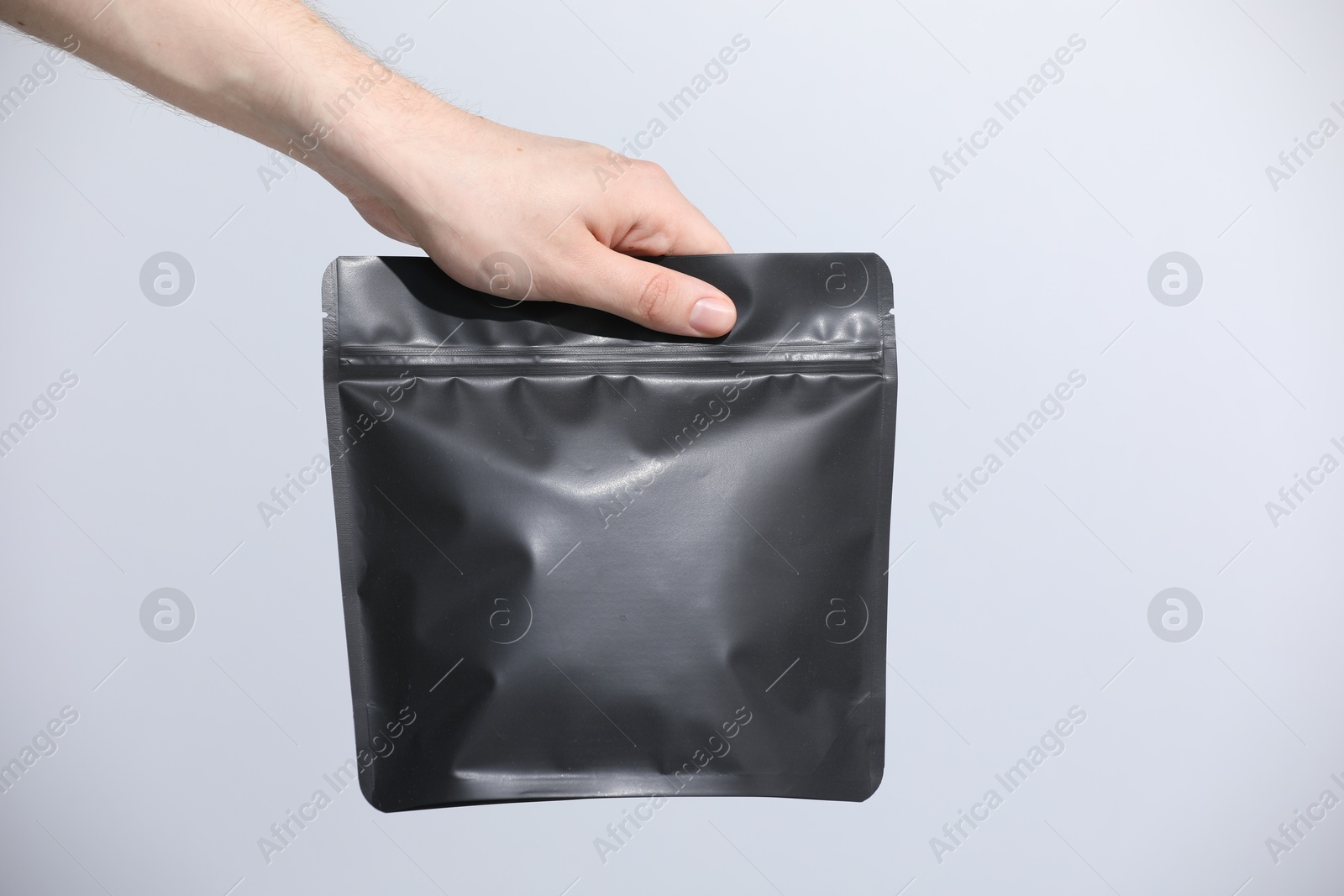 Woman holding blank zipper stand-up pouch on light grey background, closeup. Space for text Photo of Woman holding blank zipper stand-up pouch on light grey background, closeup. Space for text