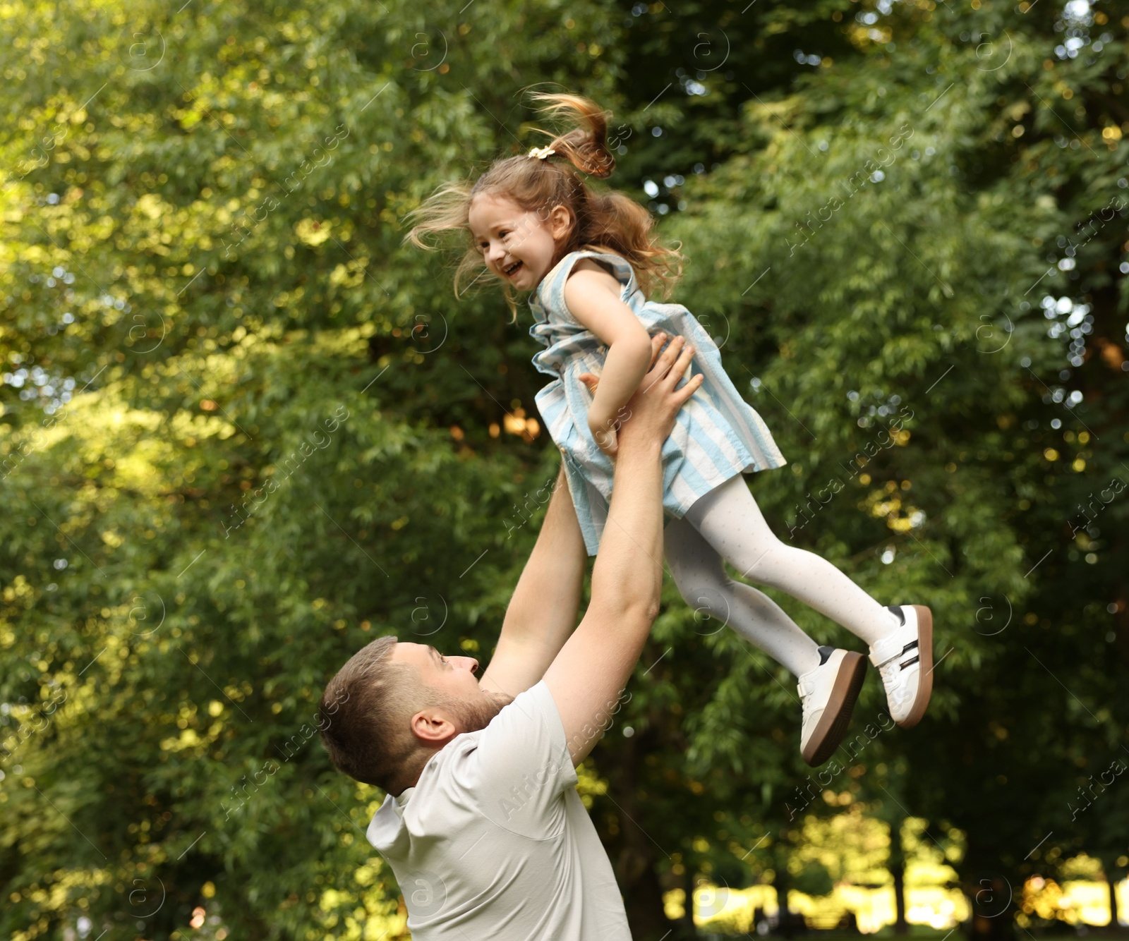 Happy Father's Day. Dad and his little daughter spending time together in park, low angle view Photo of Happy Father's Day. Dad and his little daughter spending time together in park, low angle view