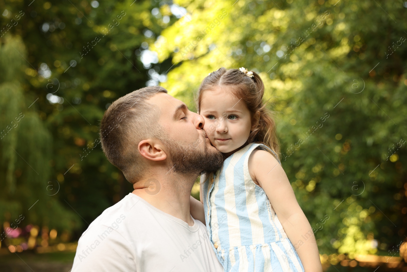 Photo of Happy Father's Day. Dad kissing his little daughter in park
