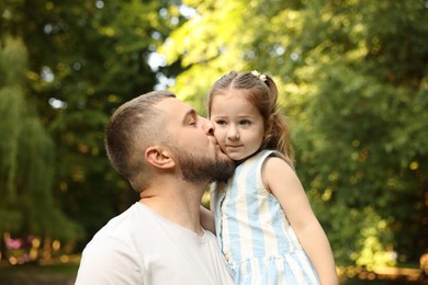 Photo of Happy Father's Day. Dad kissing his little daughter in park