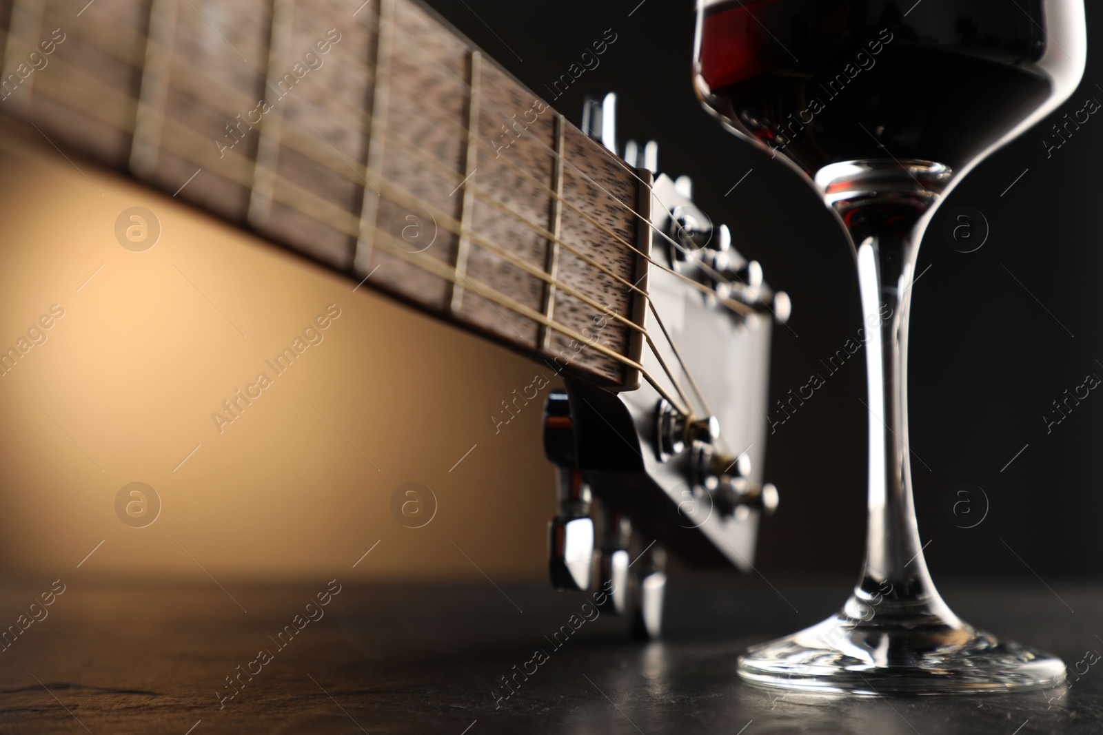 Acoustic guitar and glass of red wine on black table, closeup Photo of Acoustic guitar and glass of red wine on black table, closeup