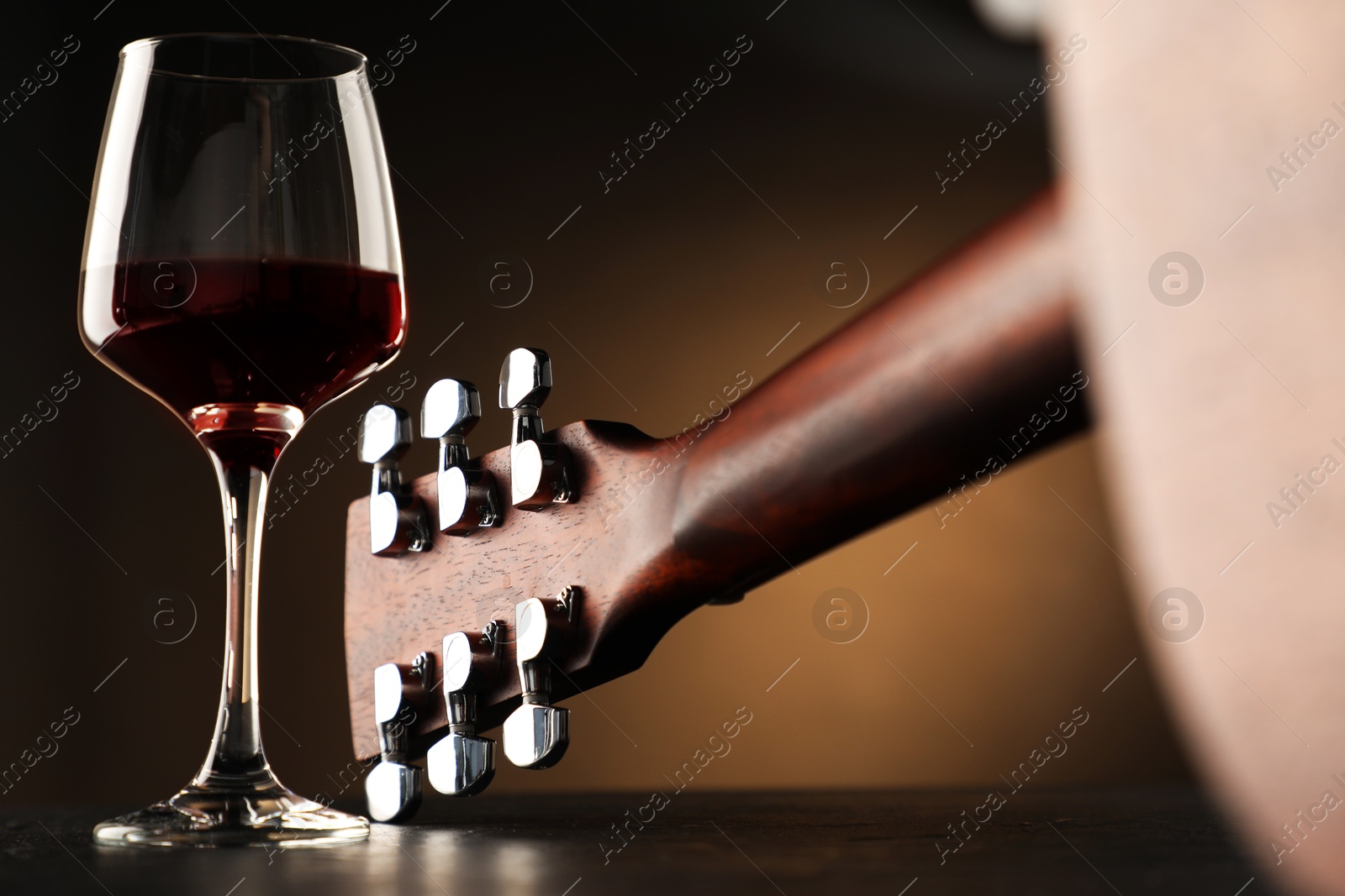 Acoustic guitar and glass of red wine on black table, closeup Photo of Acoustic guitar and glass of red wine on black table, closeup