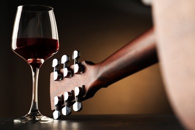 Photo of Acoustic guitar and glass of red wine on black table, closeup