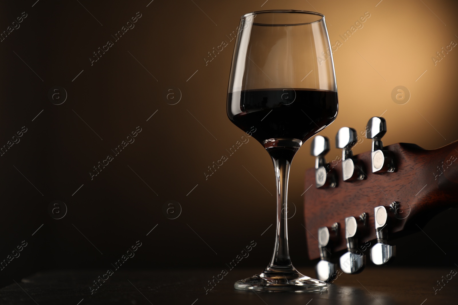 Acoustic guitar and glass of red wine on black table, closeup. Space for text Photo of Acoustic guitar and glass of red wine on black table, closeup. Space for text