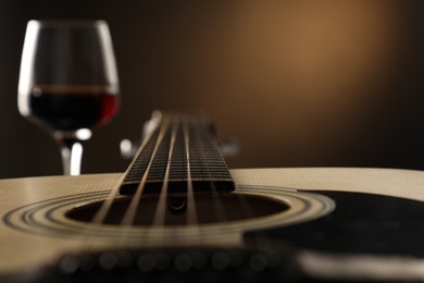 Photo of Acoustic guitar and glass of red wine on black background, closeup. Space for text