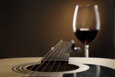 Photo of Acoustic guitar and glass of red wine on black background, closeup. Space for text