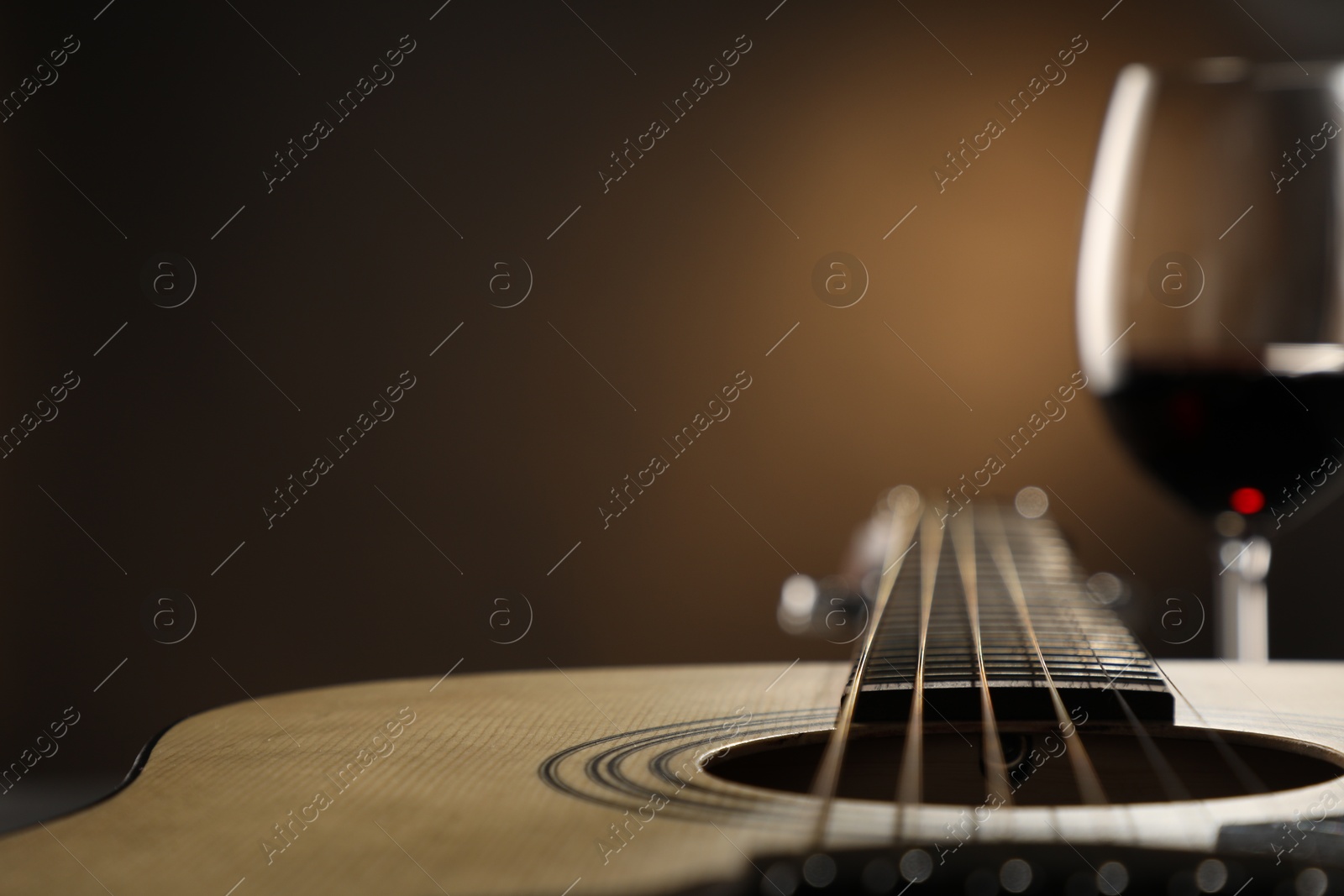 Photo of Acoustic guitar and glass of red wine on black background, closeup. Space for text