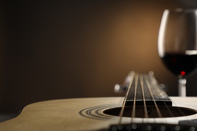 Photo of Acoustic guitar and glass of red wine on black background, closeup. Space for text
