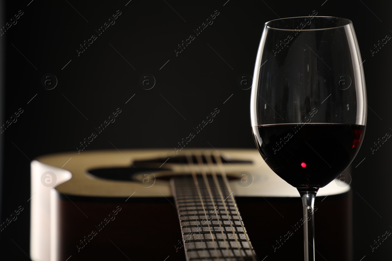 Acoustic guitar and glass of red wine on black background, closeup. Space for text Photo of Acoustic guitar and glass of red wine on black background, closeup. Space for text