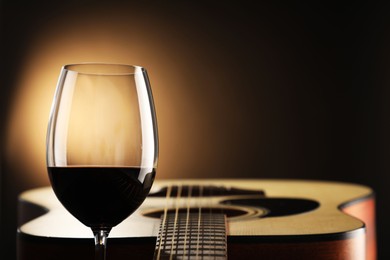 Photo of Acoustic guitar and glass of red wine on black background, closeup. Space for text