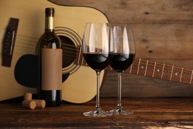 Photo of Acoustic guitar, bottle and glasses of red wine on wooden table