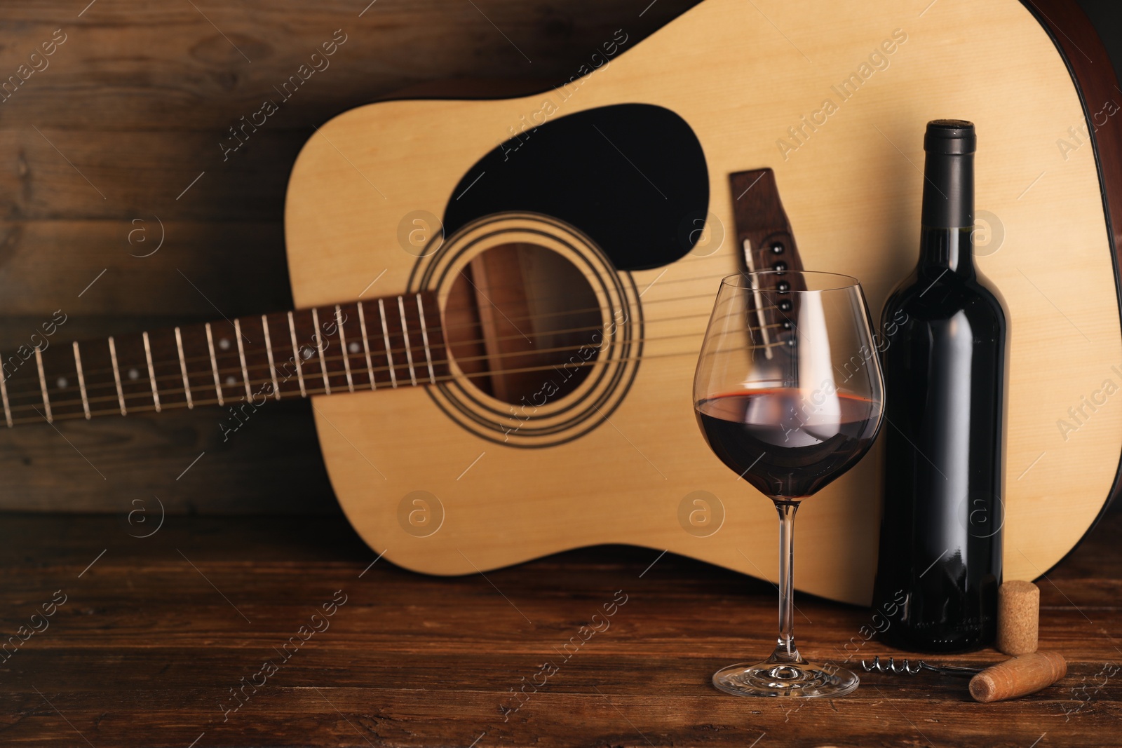 Acoustic guitar, bottle and glass of red wine on wooden table Photo of Acoustic guitar, bottle and glass of red wine on wooden table
