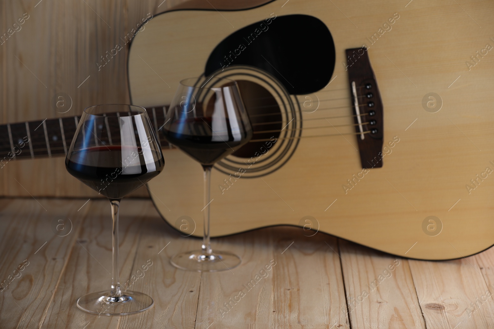 Acoustic guitar and glasses of red wine on wooden table. Space for text Photo of Acoustic guitar and glasses of red wine on wooden table. Space for text