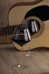 Photo of Acoustic guitar and glasses of red wine on wooden table
