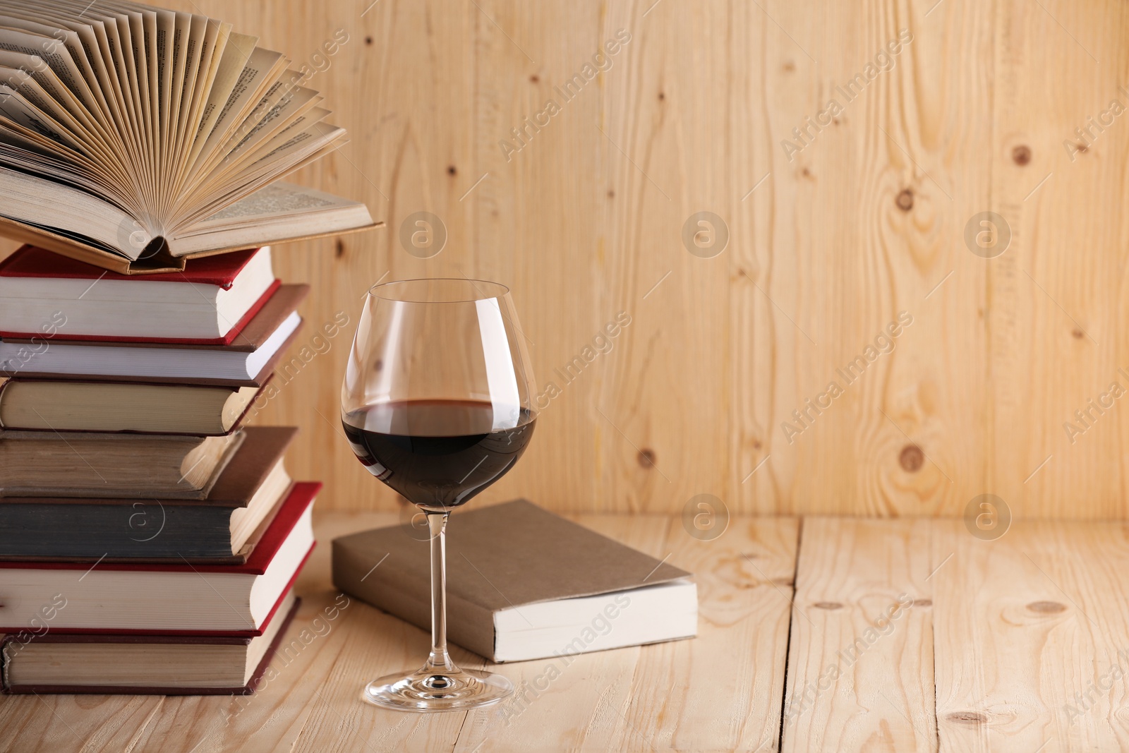 Glass of red wine and stacked books on wooden table. Space for text Photo of Glass of red wine and stacked books on wooden table. Space for text
