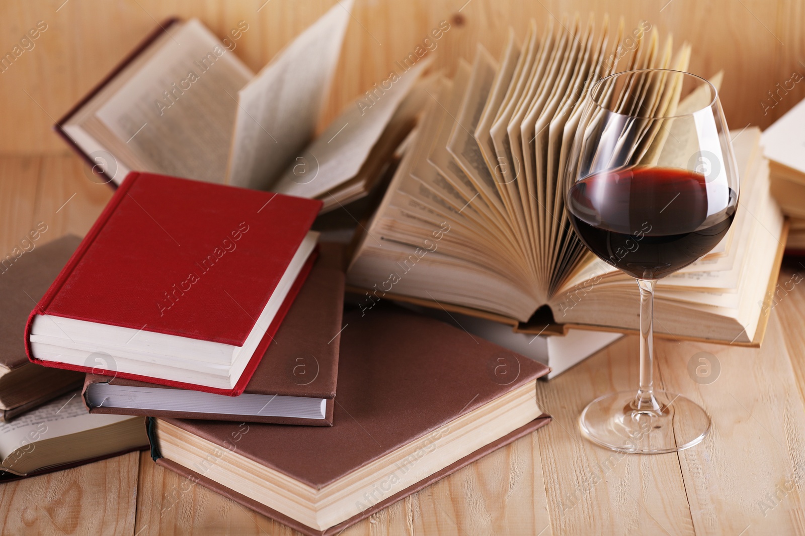 Glass of red wine and books on wooden table, closeup Photo of Glass of red wine and books on wooden table, closeup
