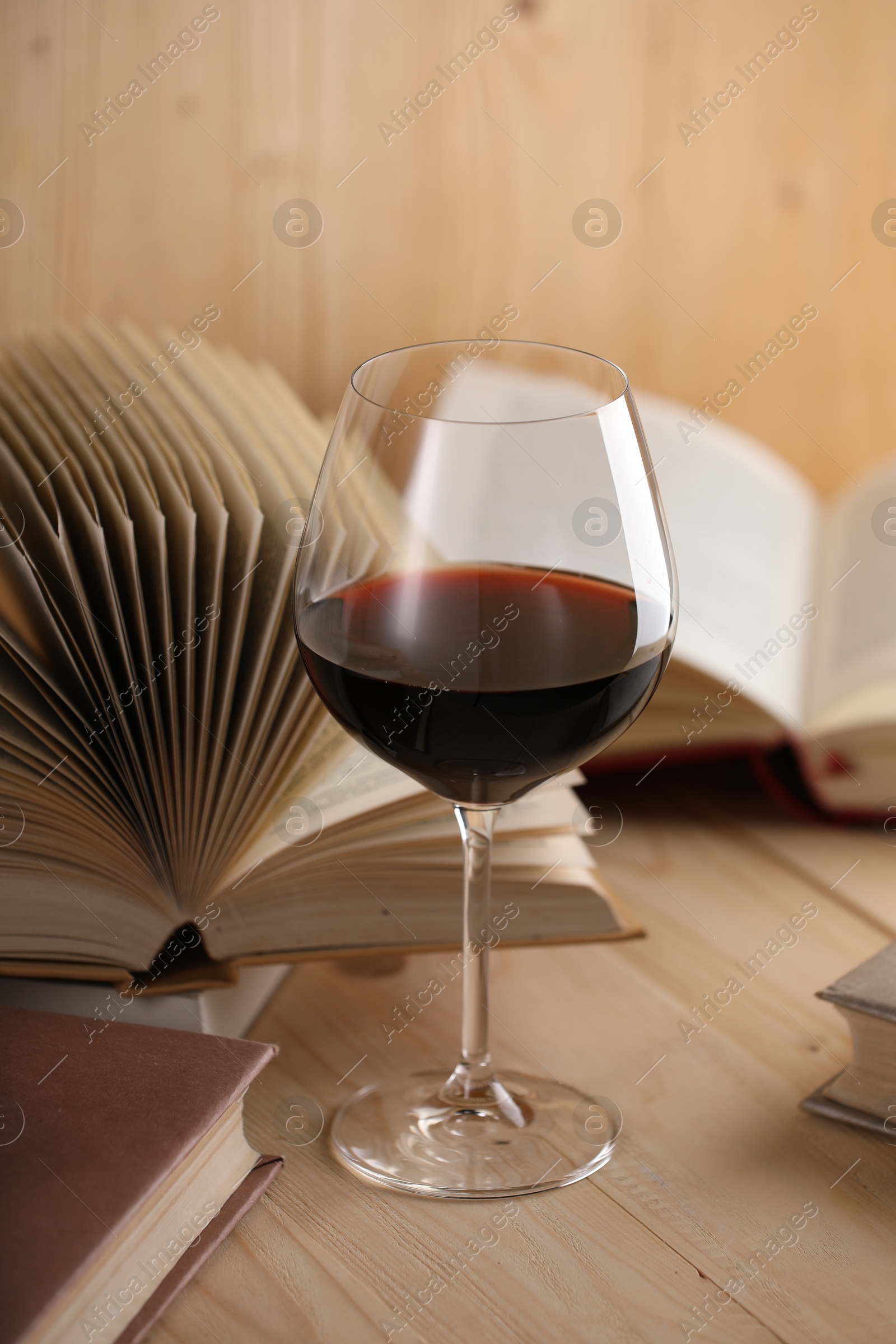 Glass of red wine and books on wooden table, closeup Photo of Glass of red wine and books on wooden table, closeup