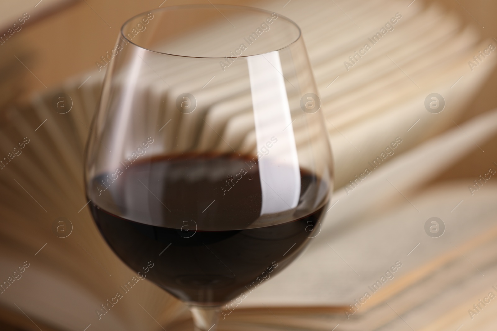 Glass of red wine and open book on table, closeup Photo of Glass of red wine and open book on table, closeup