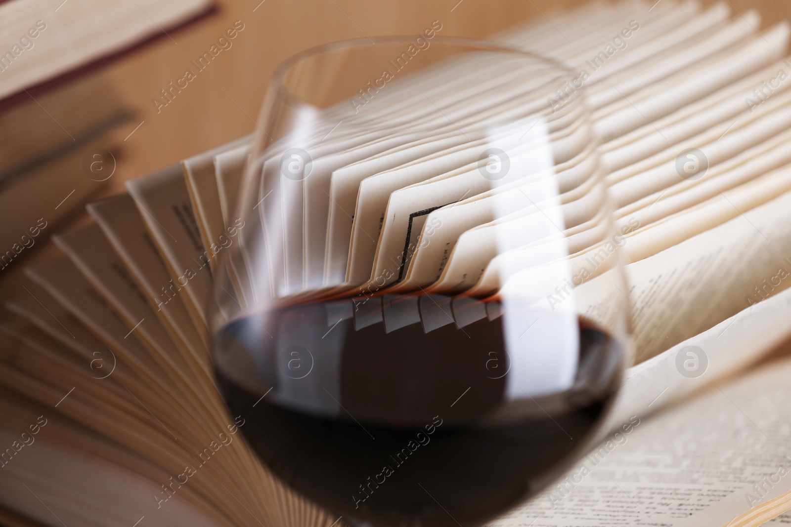 Glass of red wine and open book on table, closeup Photo of Glass of red wine and open book on table, closeup