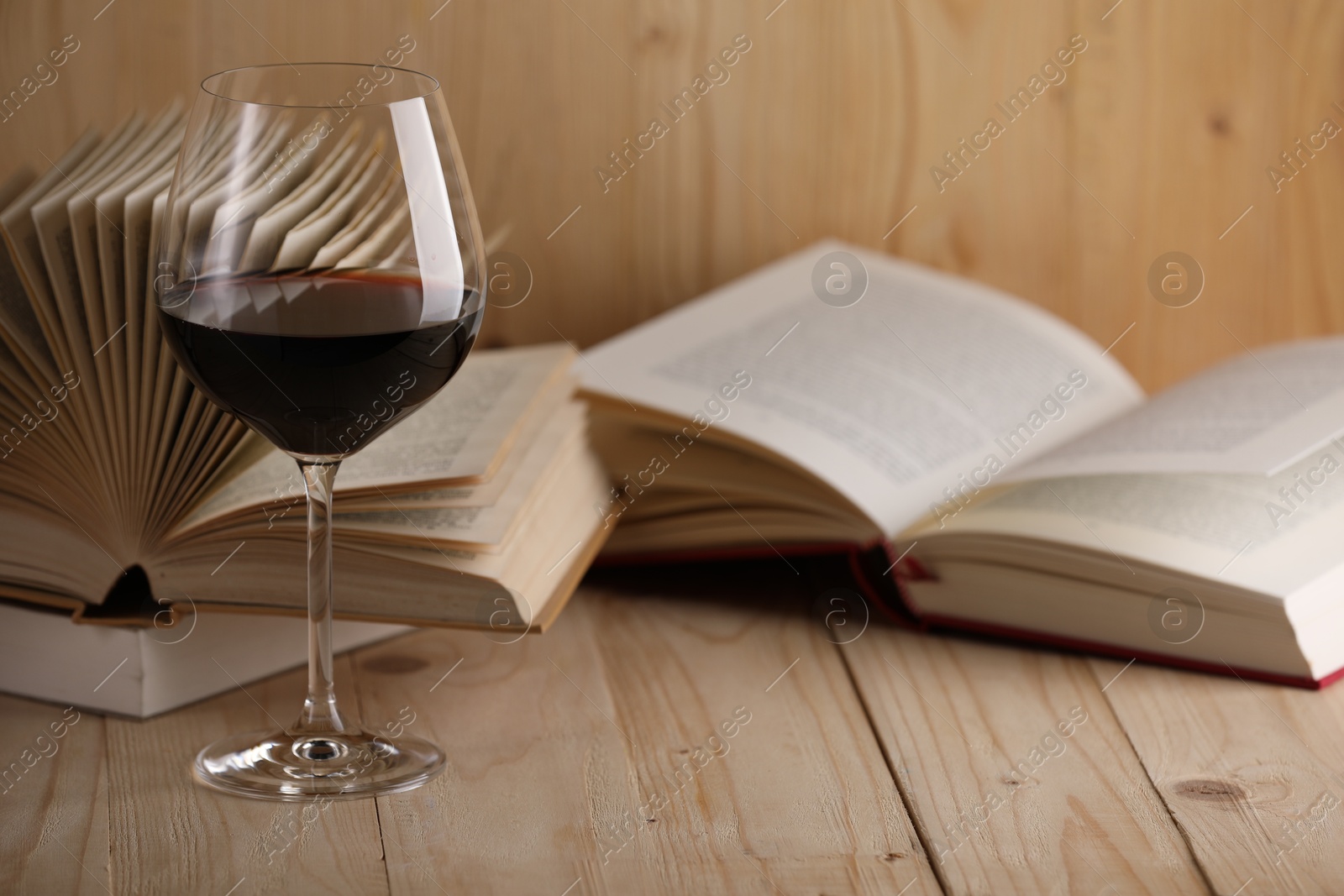 Glass of red wine and open books on wooden table, closeup. Space for text Photo of Glass of red wine and open books on wooden table, closeup. Space for text