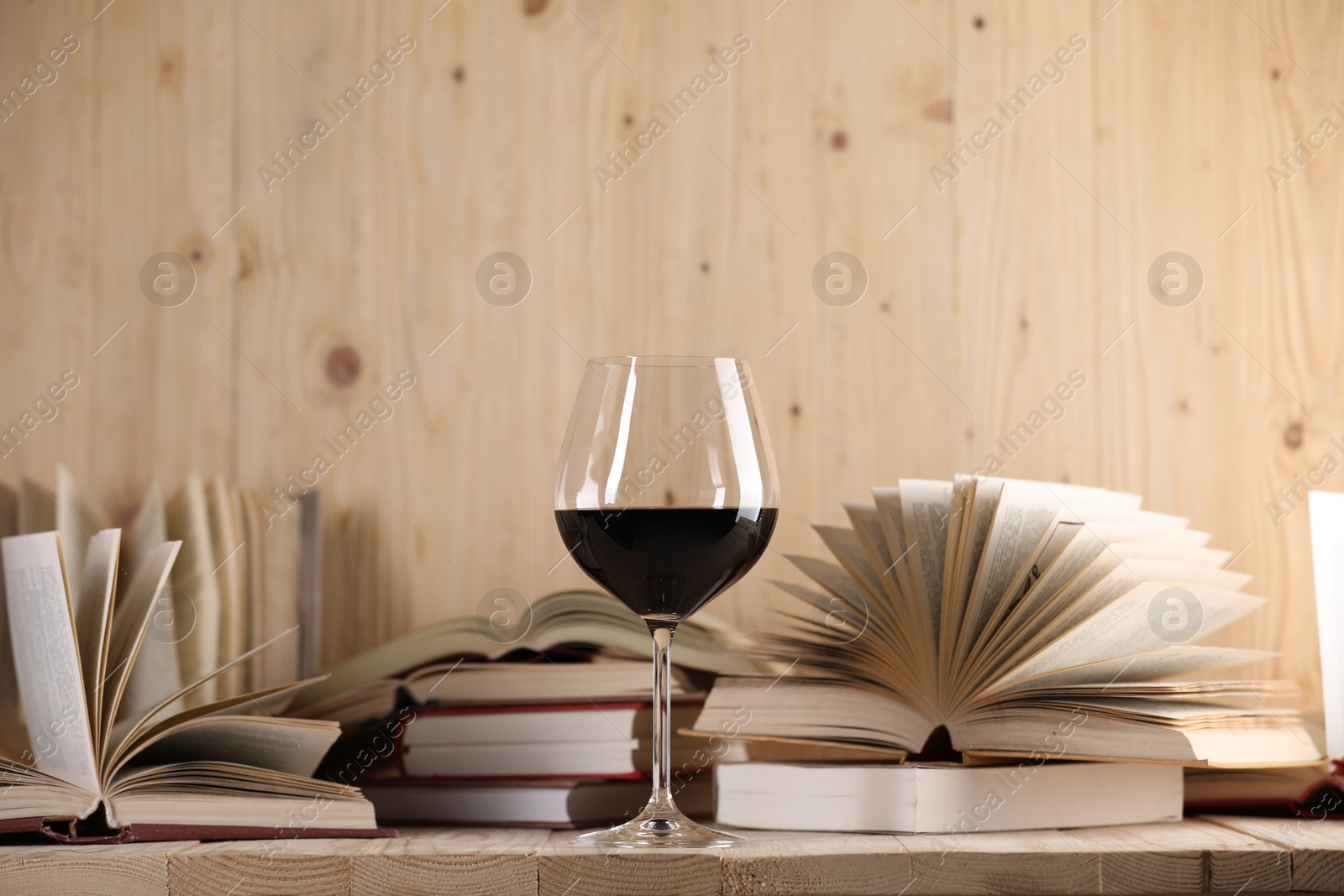Glass of red wine and open books on wooden table. Space for text Photo of Glass of red wine and open books on wooden table. Space for text